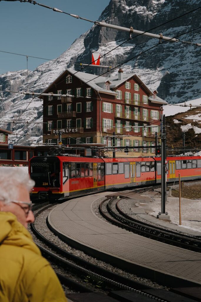 A train travels through a snowy Swiss mountain village with a scenic hotel backdrop, capturing winter charm.